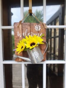 Welcome sign with watering can and flowers