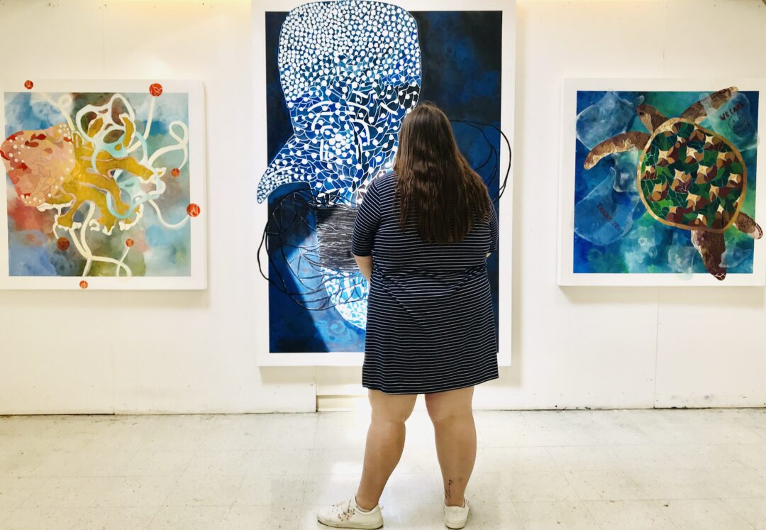 Girl standing in front of row of paintings
